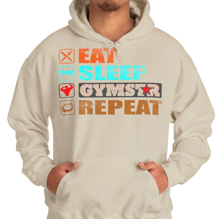 A man wearing a light beige hoodie with a colorful graphic on the chest that reads 'EAT SLEEP GYMSTAR REPEAT' with small icons, paired with blue jeans, against a plain white background.