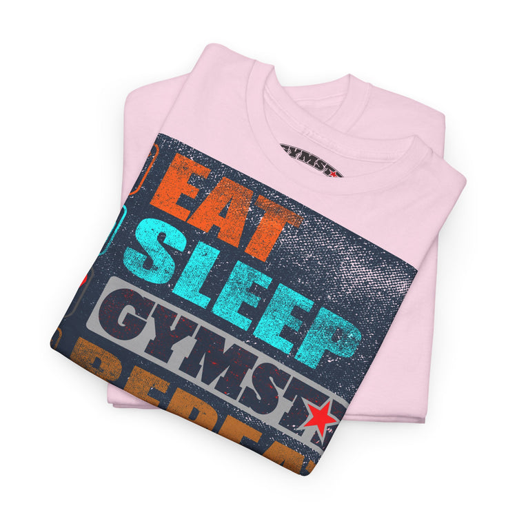A folded light pink t-shirt with a distressed graphic print reading 'EAT SLEEP GYMST' in orange, teal, and dark gray lettering, displayed on a clean white background.