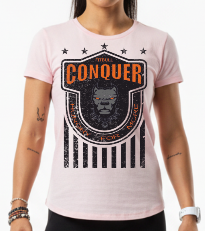 Woman wearing a pink Fitbull t-shirt witha motivational design Conquer, a logo and black leggings.