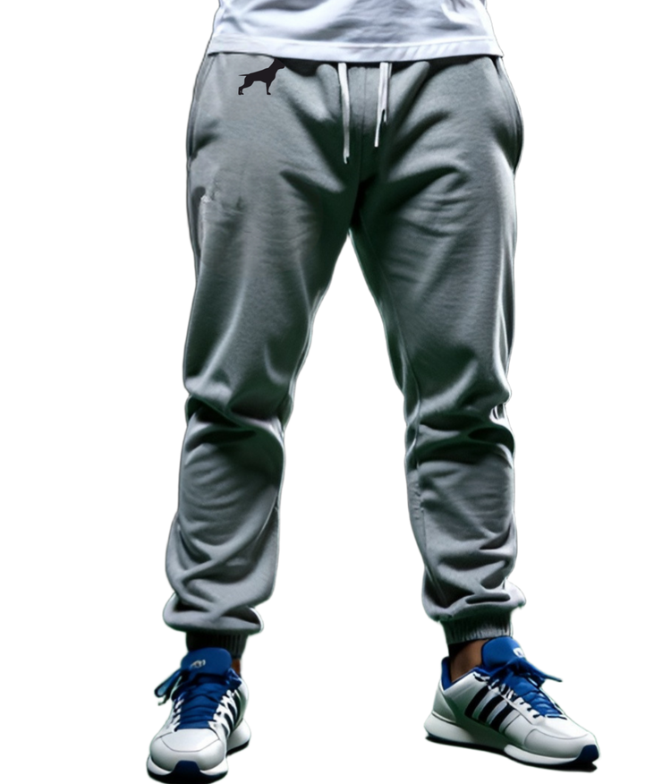 Ein Mann in einem Sport-T-Shirt und Fitbull-Jogginghosen steht da und verschränkt trotzig die Arme vor der Brust.