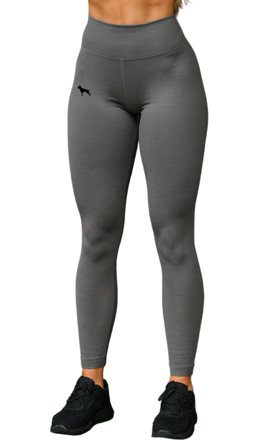 Woman in grеy athletic leggings from Fitbull fit wear, lifting dumbbells.