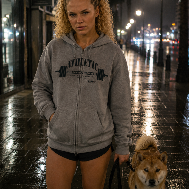 Woman in a gray Gymstar Athletic hoodie with a dog on a city street at night
