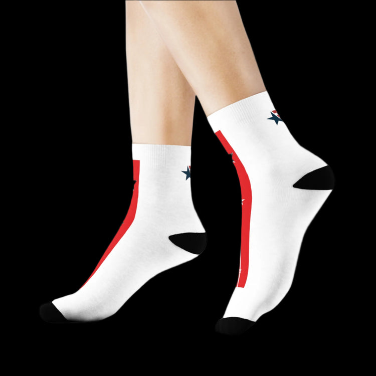 A pair of white crew training socks with red and blue accents and a star pattern on the side seams, displayed on a person's legs against a black background.