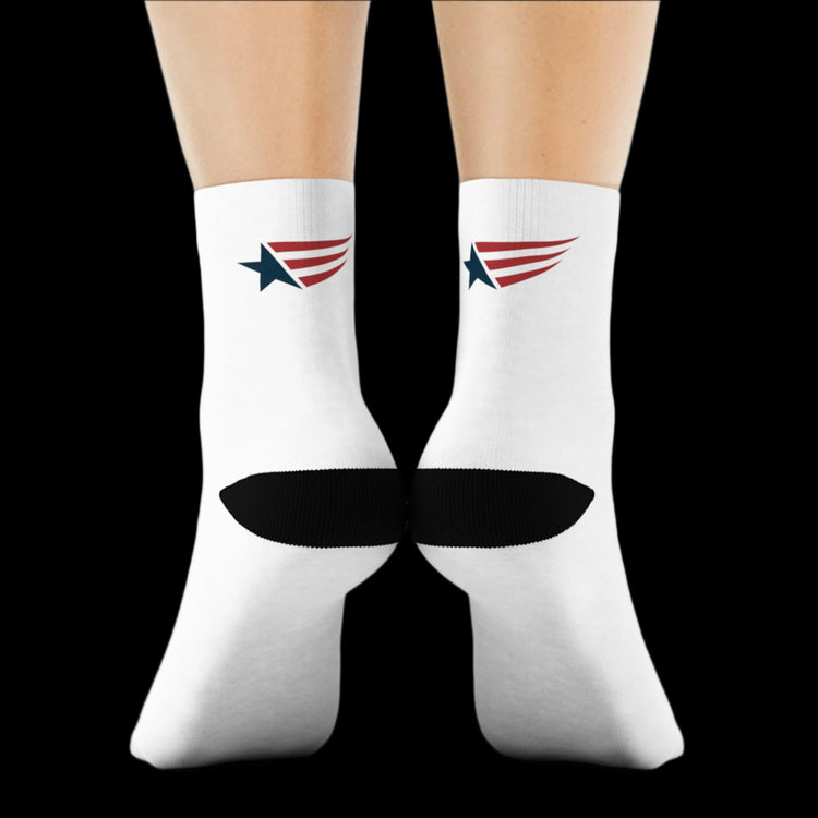 A pair of white crew training socks with red and blue accents and a star pattern on the side seams, displayed on a person's legs against a black. Rear view.