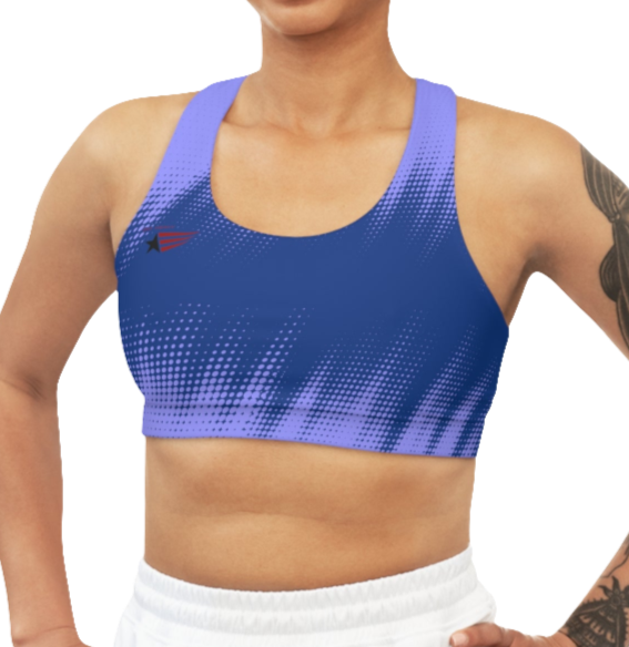 A women's athletic sports bra. It is primarily blue with a bright blue, dotted, gradient pattern that radiates from the sides and bottom. The straps are solid red. A small logo featuring a star and three red and blue stripes is on the left side of the chest.