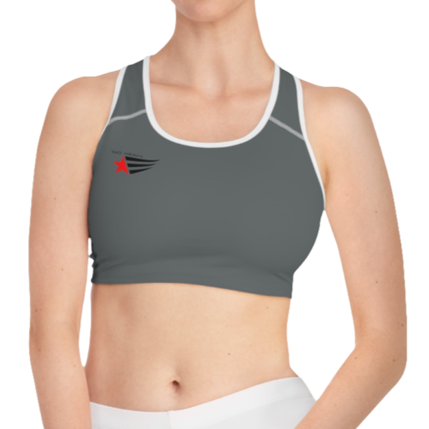 A women's solid grey athletic sports bra Gymsatr. It features white trim around the neckline and armholes. A logo with a red star and three black stripes is on the left side of the chest, with the text "GO HEAVY" above it.