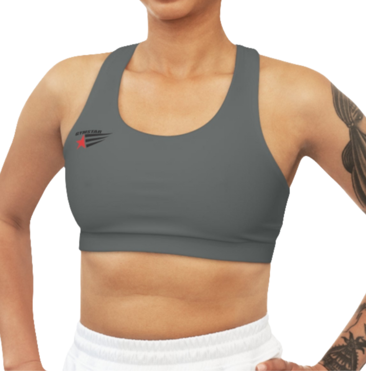 A women's solid grey athletic sports bra. It has a scoop neckline and a racerback fitness style. A small logo featuring a star and three red and blue stripes is on the left side of the chest, with the brand name "GYMSTAR" above it.