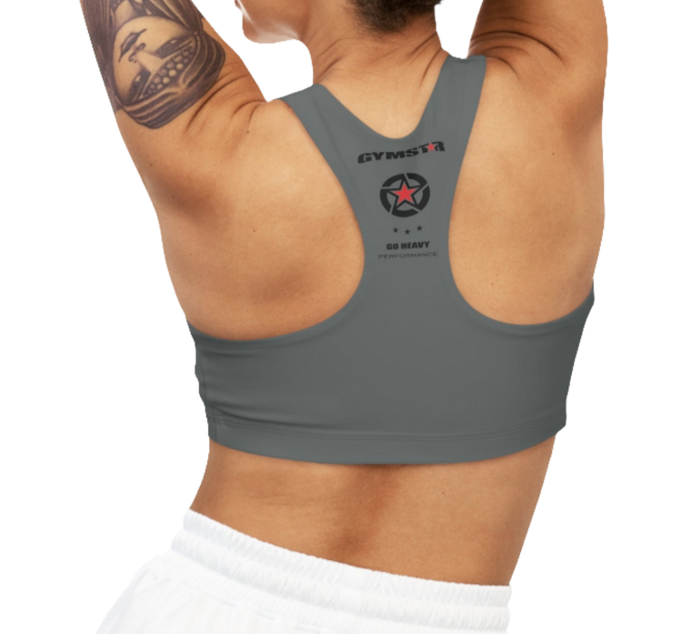 A women's solid gray athletic sports bra, shown from the back. It has a racerback style. The brand's logo, a red star within a circle of smaller stars, is printed on the upper back, along with the "GYMSTAR" brand name and the tagline "GO HEAVY PERFORMANCE."