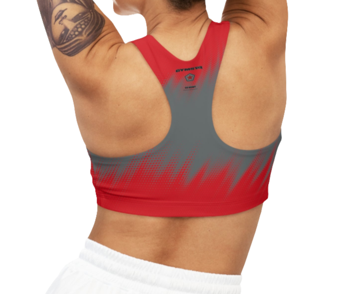 A women wearing athletic sports bra, shown from the back. The main body is gray with a red, dotted, gradient pattern that radiates from the bottom. The straps are solid red and form a racerback style. The brand name "GYMSTAR" and a logo are visible on the back, between the shoulder blades.