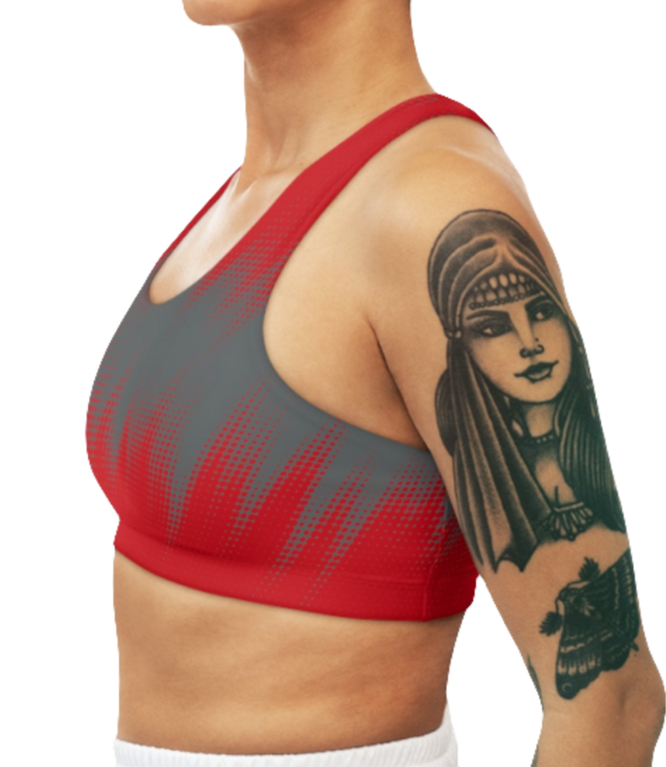 A women wearing athletic sports bra, shown from the back. The main body is gray with a red, dotted, gradient pattern that radiates from the bottom. The straps are solid red and form a racerback style. Left side view.