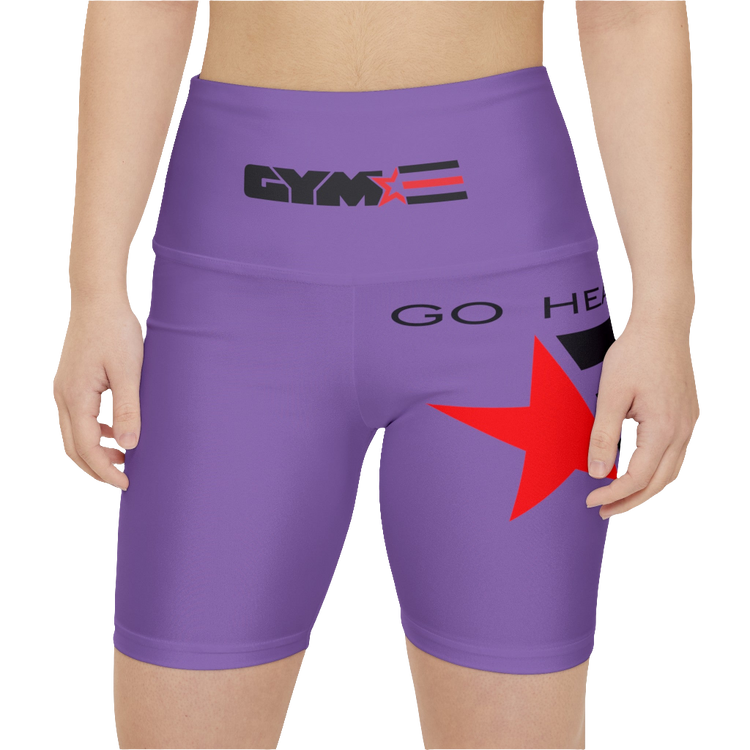 A woman wearings pair of purple Gymstar women's workout leggings with 'GYMSTAR' and 'GO HEAVY' text, along with a star graphic, on a person mid-section view. front close up view.