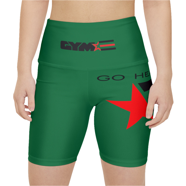 A woman wearings pair of green fitness leggings with a red star and 'GYMSTAR' logo on the upper left leg, waistband, and a 'GO HEAVY' text on the right side of the waistband. Front close up view.