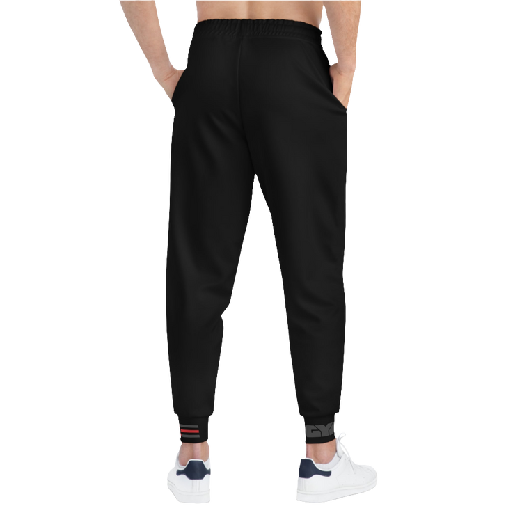 A person standing backways, wearing black joggers Gymstar with a logoand white sneakers. The joggers have a ribbed bottom and waistband cuffs, and feature two side pockets.