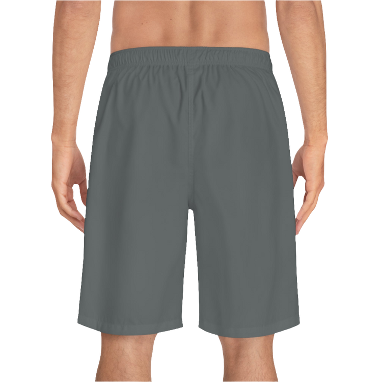 A man wearing grey sports shorts with an elastic waistband and drawstrings, featuring a logo on the left leg  back side view.