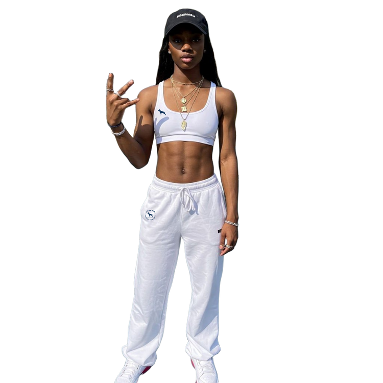 Person wearing a white sports Fitbull bra and pants with a black cap on a white background