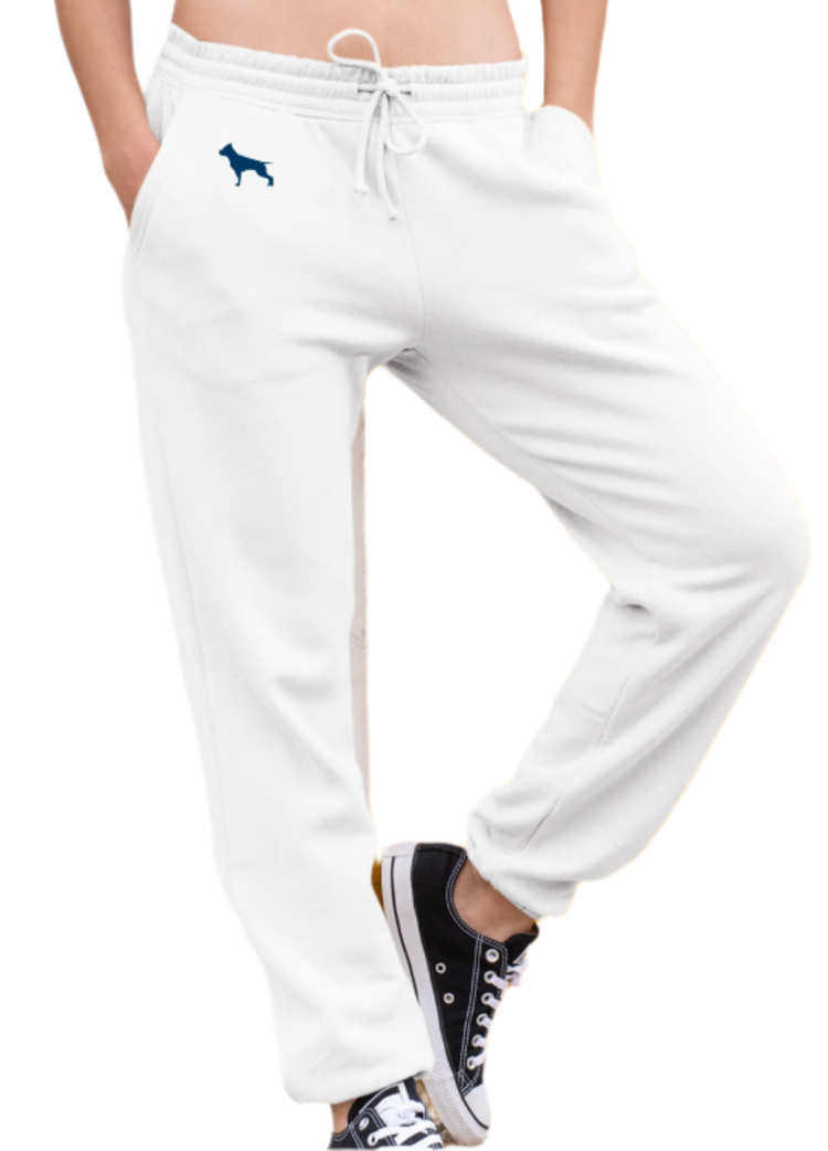 Eine Frau trägt weisse Fitbull-Jogginghosen mit dem Logo der Marke und ein sportliches weisse Tanktop.
