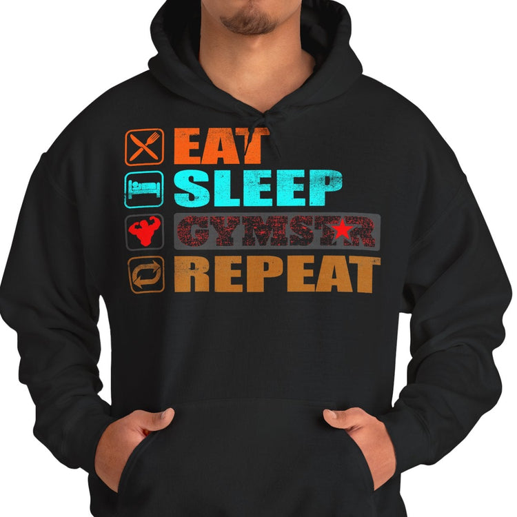 A man wearing a black pullover hoodie with a colorful graphic on the chest that reads 'EAT SLEEP GYMSTAR REPEAT' with corresponding icons, paired with blue jeans against a plain white background.