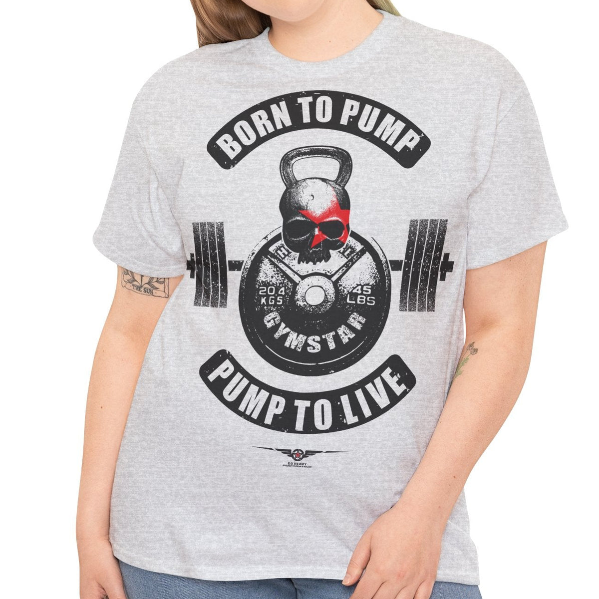 A woman modeling a light heather gray t-shirt with a black and red gym-themed graphic that reads 'BORN TO PUMP' and 'PUMP TO LIVE' around a kettlebell and barbell design.