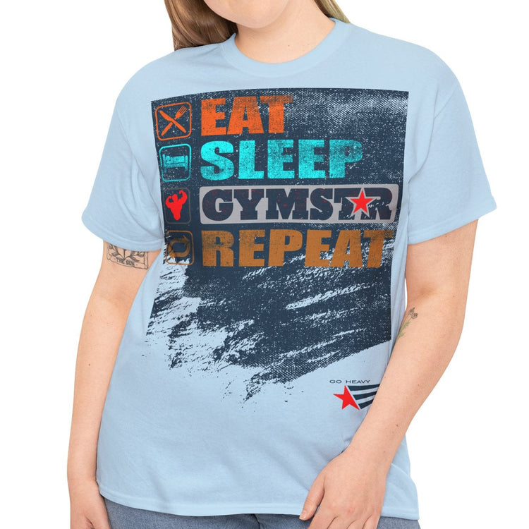 A woman modeling a light blue graphic t-shirt with the text 'EAT SLEEP GYMSTAR REPEAT' in colorful block letters over a distressed dark blue paint-splatter design. She is also wearing blue jeans, set against a plain white background.