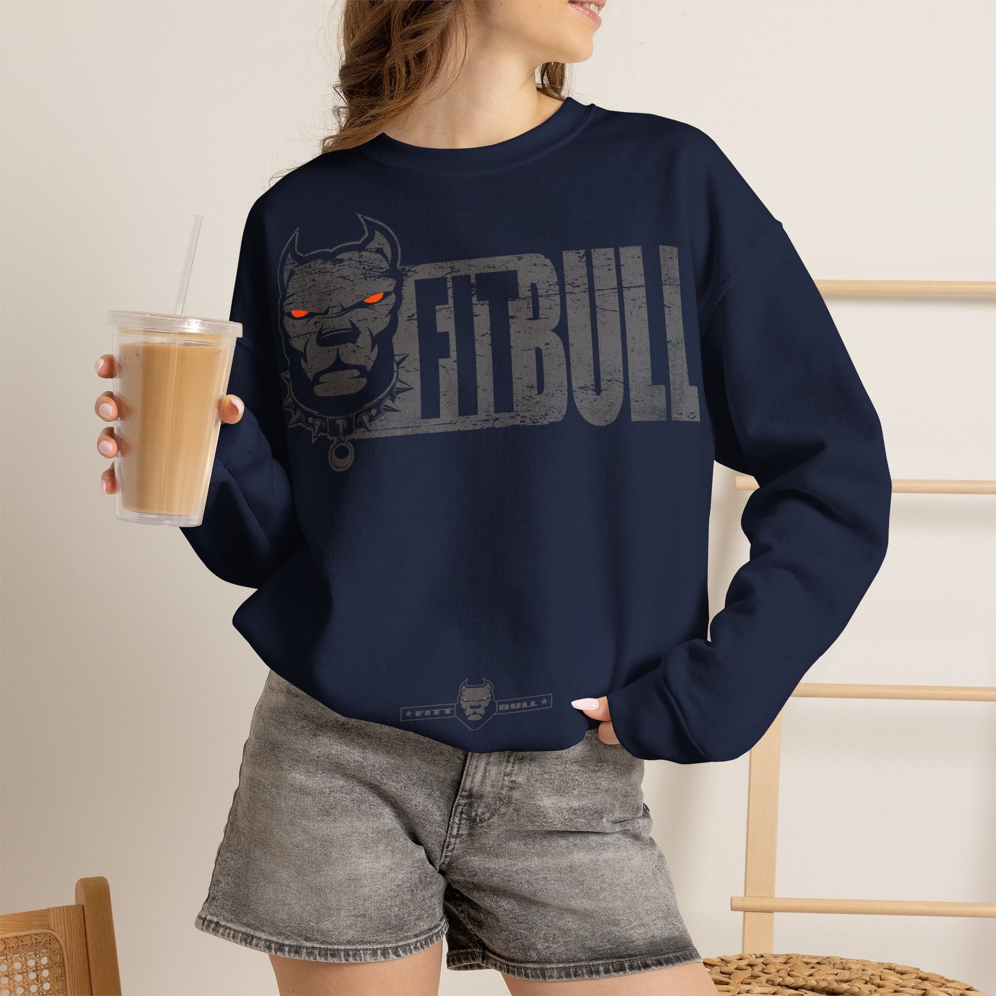 Person wearing a navy blue Fitbull sweatshirt , holding a drink.
