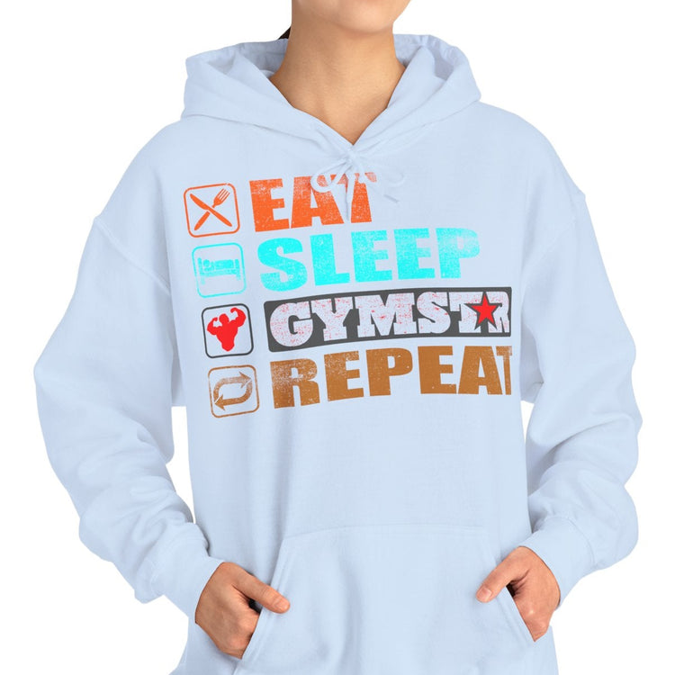 A woman modeling a light blue hoodie with a colorful graphic on the chest that reads 'EAT SLEEP GYMSTAR REPEAT' with small icons, set against a plain white background.