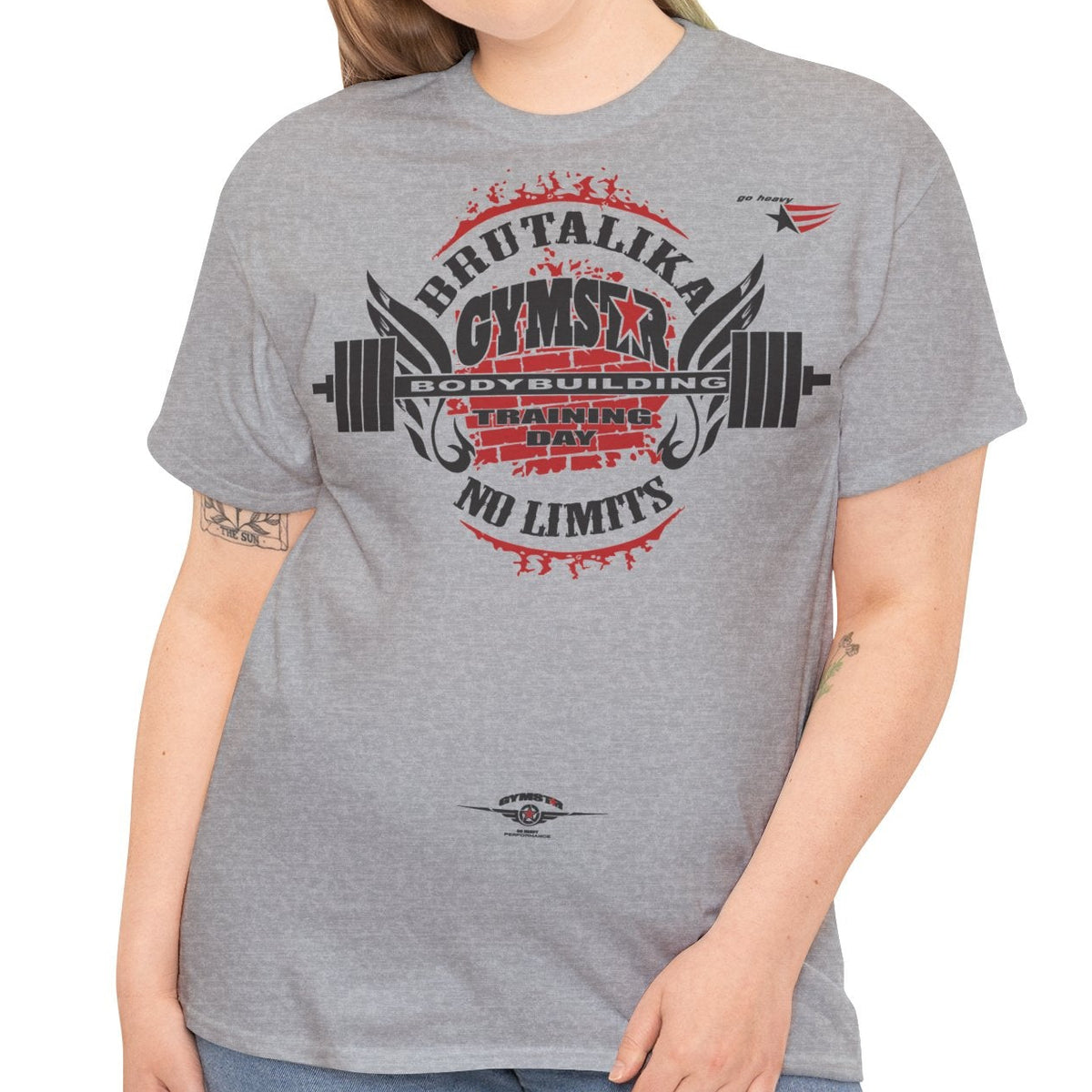 A woman modeling a heather gray t-shirt with a distressed red and black graphic that reads 'BRUTALIKA GYMSTAR NO LIMITS' with a barbell design, paired with blue jeans against a plain white background.