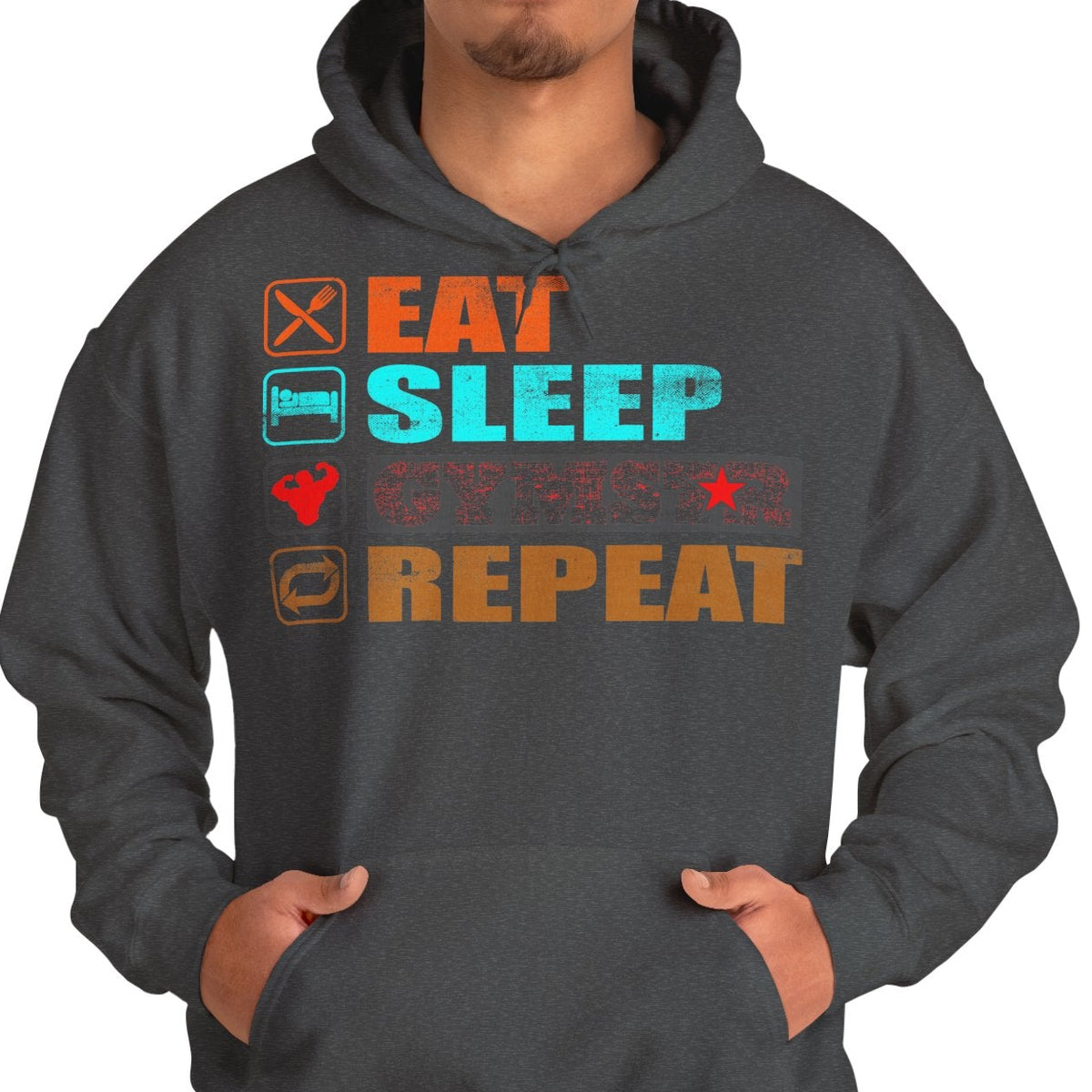 A man wearing a dark gray hoodie with a colorful graphic on the chest that reads 'EAT SLEEP GYMSTAR REPEAT' with small icons, paired with blue jeans against a plain white background.