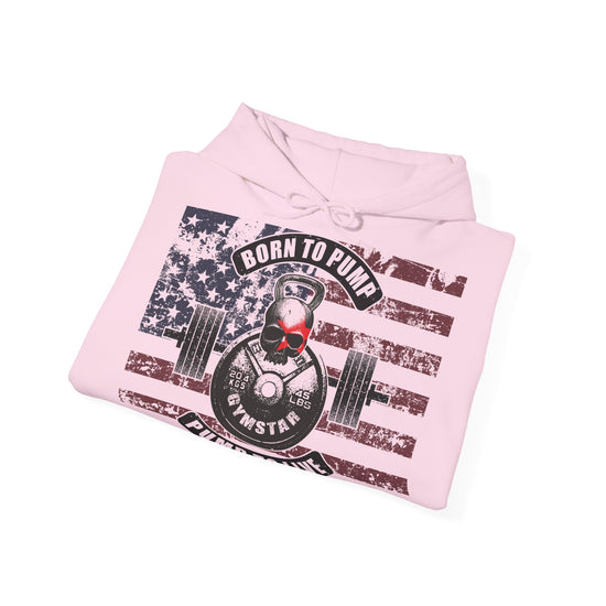 A folded light pink hoodie on a white background, featuring a distressed graphic print of an American flag with a skull wearing red sunglasses lifting a kettlebell and barbell, with the text 'BORN TO PUMP' and 'BORNSTAR'.