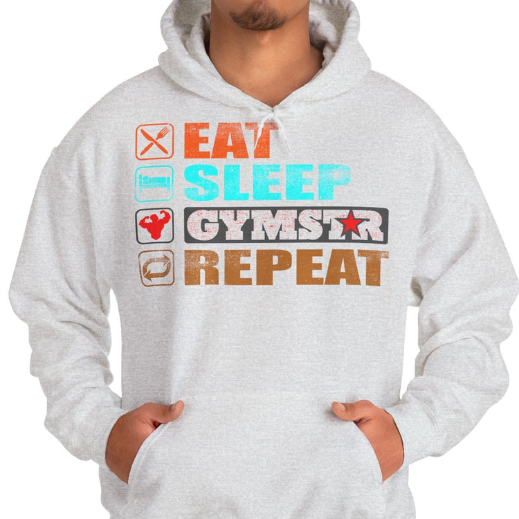 A man wearing a light gray heather pullover hoodie with a colorful graphic on the chest that reads 'EAT SLEEP GYMNS REPEAT' with small fitness icons, paired with blue jeans against a plain white background.