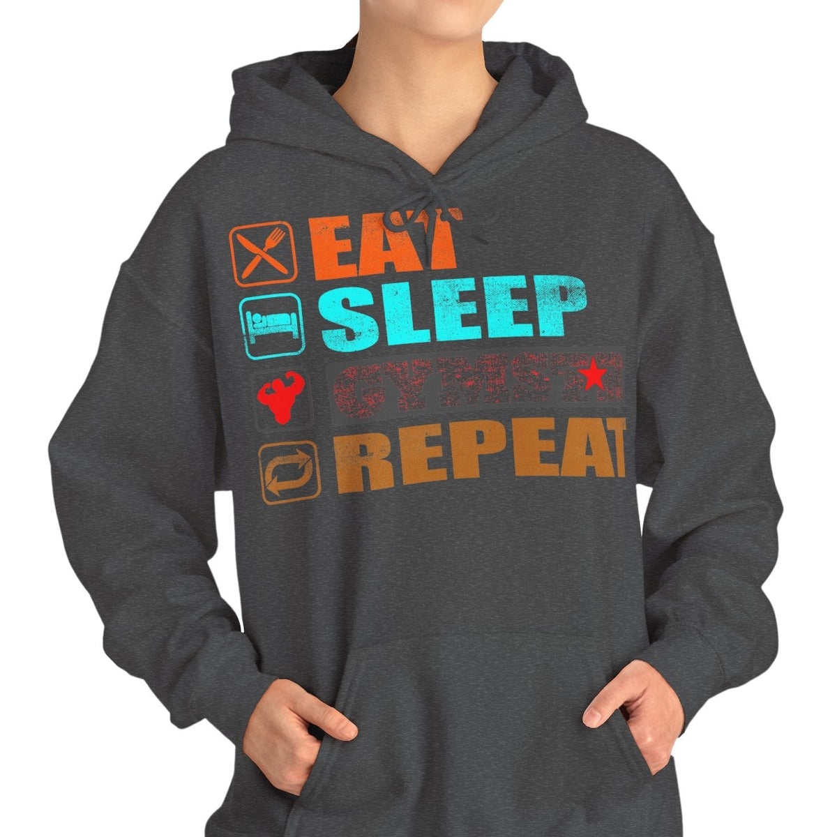A woman modeling a dark gray pullover hoodie with a colorful graphic on the chest that reads 'EAT SLEEP GYMSTAR REPEAT' with small icons, against a plain white background.