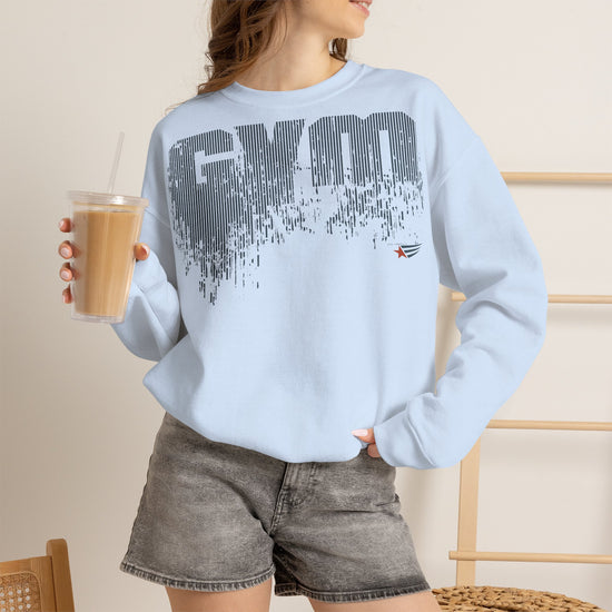 A woman wearing a light blue crewneck sweatshirt with a dark gray 'GYM' graphic and a small red star logo, paired with gray denim shorts and holding an iced coffee.