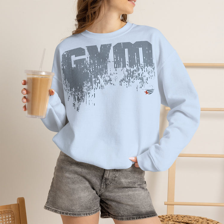 A woman wearing a light blue crewneck sweatshirt with a dark gray 'GYM' graphic and a small red star logo, paired with gray denim shorts and holding an iced coffee.