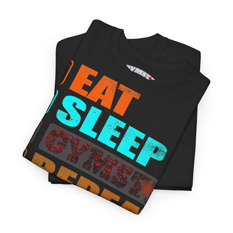 A folded black t-shirt with a colorful graphic text design reading 'EAT SLEEP CYMBAL REPEAT' in orange, cyan, and red distressed lettering, shown on a plain white background.