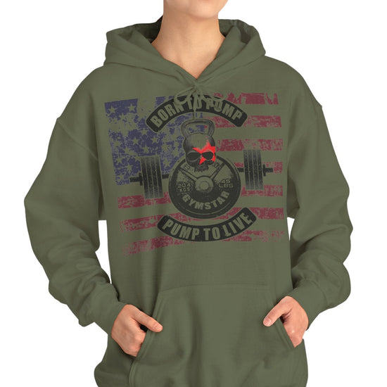 A woman modeling an olive green pullover hoodie with a distressed patriotic graphic on the front featuring a weight plate, barbell, and the words 'Rock the Pump' and 'Pump to Live'.