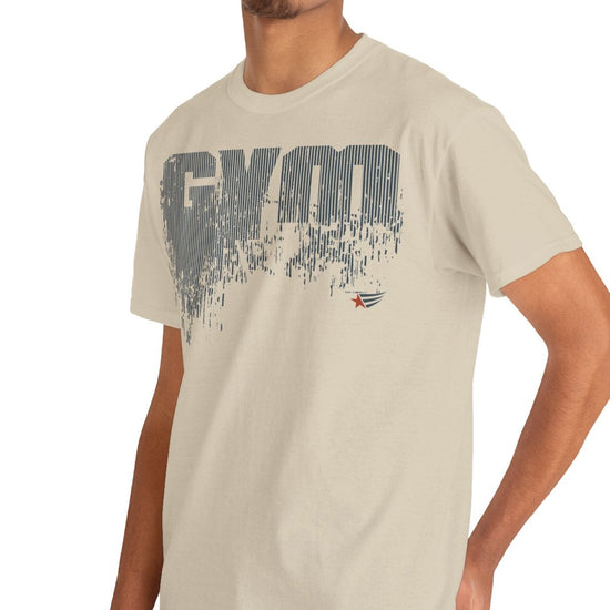 A man wearing a light beige crewneck t-shirt with a distressed gray 'GYM' graphic on the chest, paired with blue jeans, photographed against a solid white background.