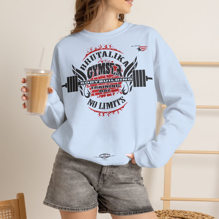 A woman wearing a light blue crewneck fitness sweatshirt with a gym-themed graphic print, paired with gray denim shorts and holding an iced coffee.