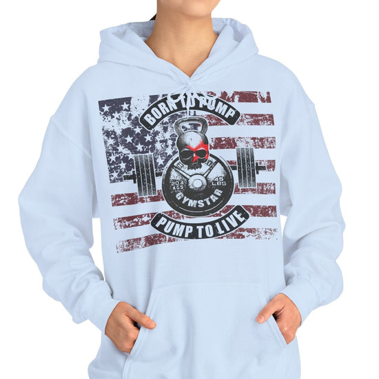 A woman modeling a light blue pullover hoodie with a large patriotic graphic on the front featuring an American flag, a weight plate, and the text 'ROCK THE BUMP CLIMP TO LIFE'.