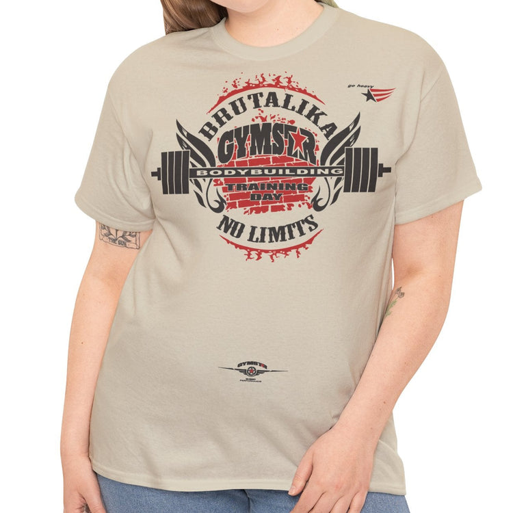A woman modeling a light beige graphic t-shirt with a red and black gym-themed print that reads 'BRUTALIKA GYMSTAR NO LIMITS' with a barbell graphic, paired with blue jeans against a plain white background.