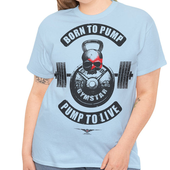 A woman modeling a light blue crewneck t-shirt with a gym-themed graphic that reads 'BORN TO PUMP' and 'PUMP TO LIVE' around a kettlebell and barbell design.