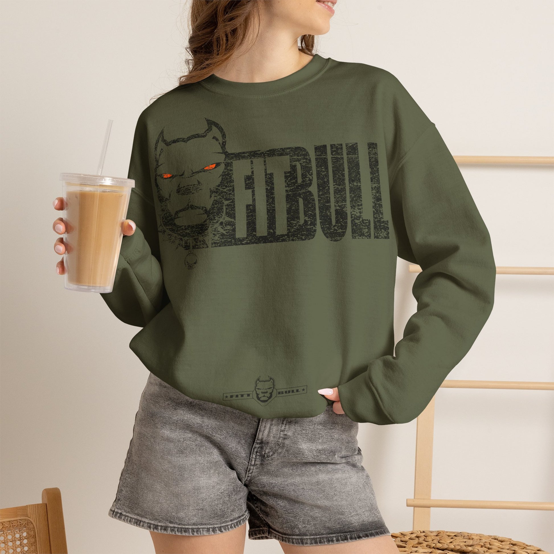 Person wearing a green sweatshirt with 'FITBULL ART' and a nebula design, holding a drink.