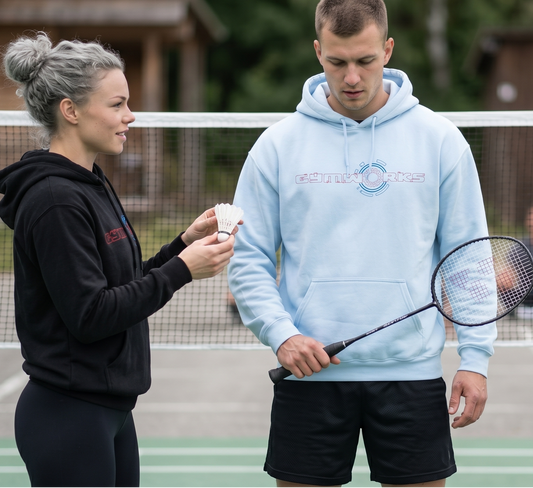 Two people on a badminton court with Gymworks hoodie one holding a racket and the other holding a cup.