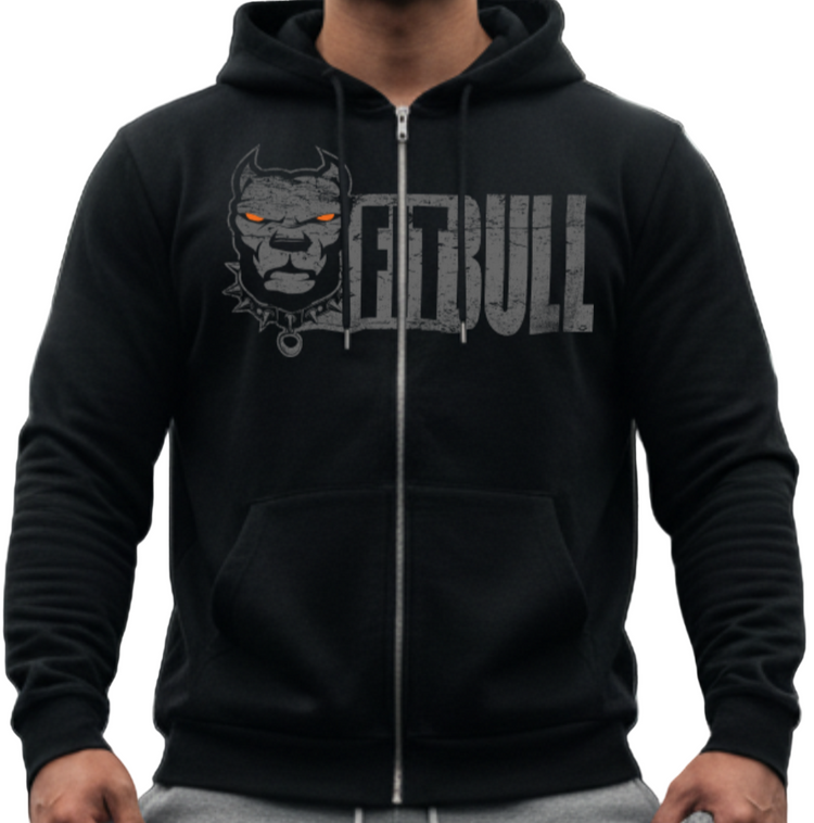 Person wearing a black Fitbull fitness hoodie with a logo and text, gray pants, and red sneakers in a gym setting.