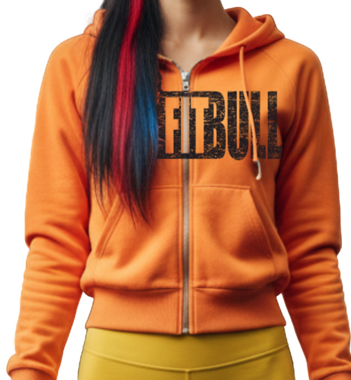 Woman in orange Fitbull fitness hoodie and yellow leggings standing in a gym.