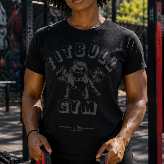Person wearing a Fitbul Gym t-shirt holding resistance bands in an outdoor setting.