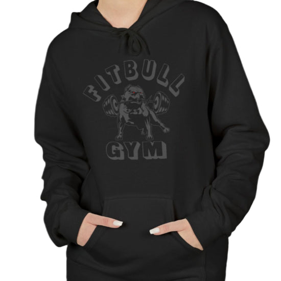 A woman wearing a black, sporty hoodie for fitness and crossfit by the Fitbull brand, branded with a logo and a motivating motif.