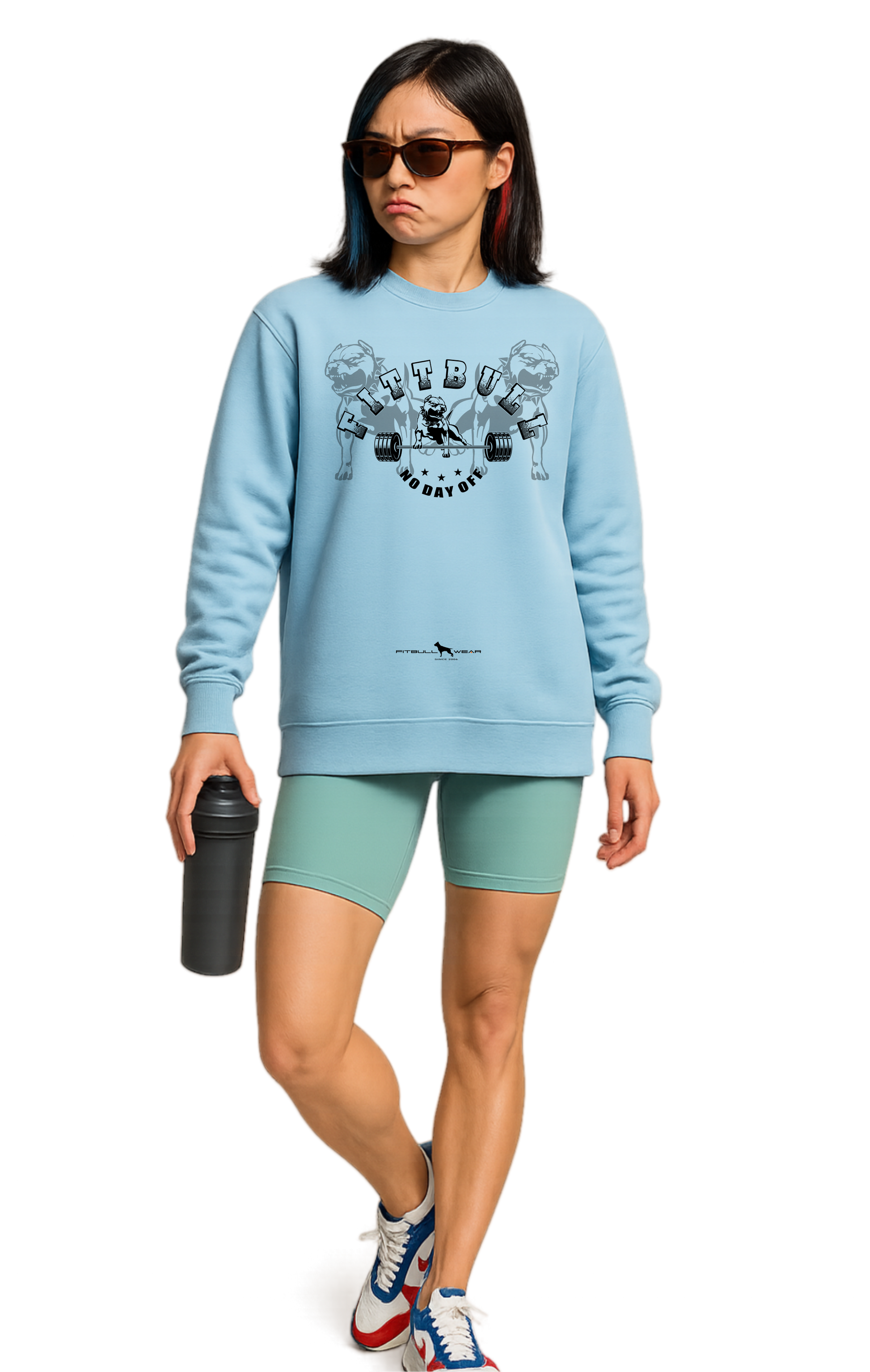 Woman wearing a light blue sweatshirt Fitbull with graphic No Day Off design, green shorts, and colorful sneakers on a white background.
