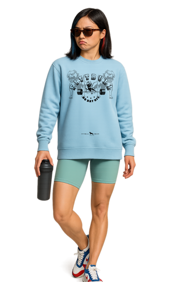 Woman wearing a light blue sweatshirt Fitbull with graphic No Day Off design, green shorts, and colorful sneakers on a white background.