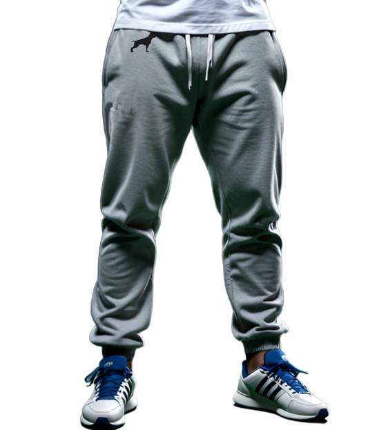 Ein Mann in einem Sport-T-Shirt und Fitbull-Jogginghosen steht da und verschränkt trotzig die Arme vor der Brust.