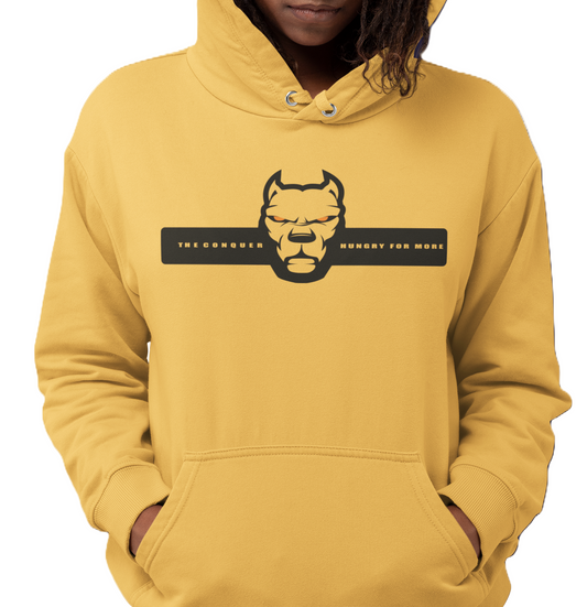 A woman wearing Yellow Fitbull hoodie with a motivation dog graphic and text The Conquer Hungry For More.
