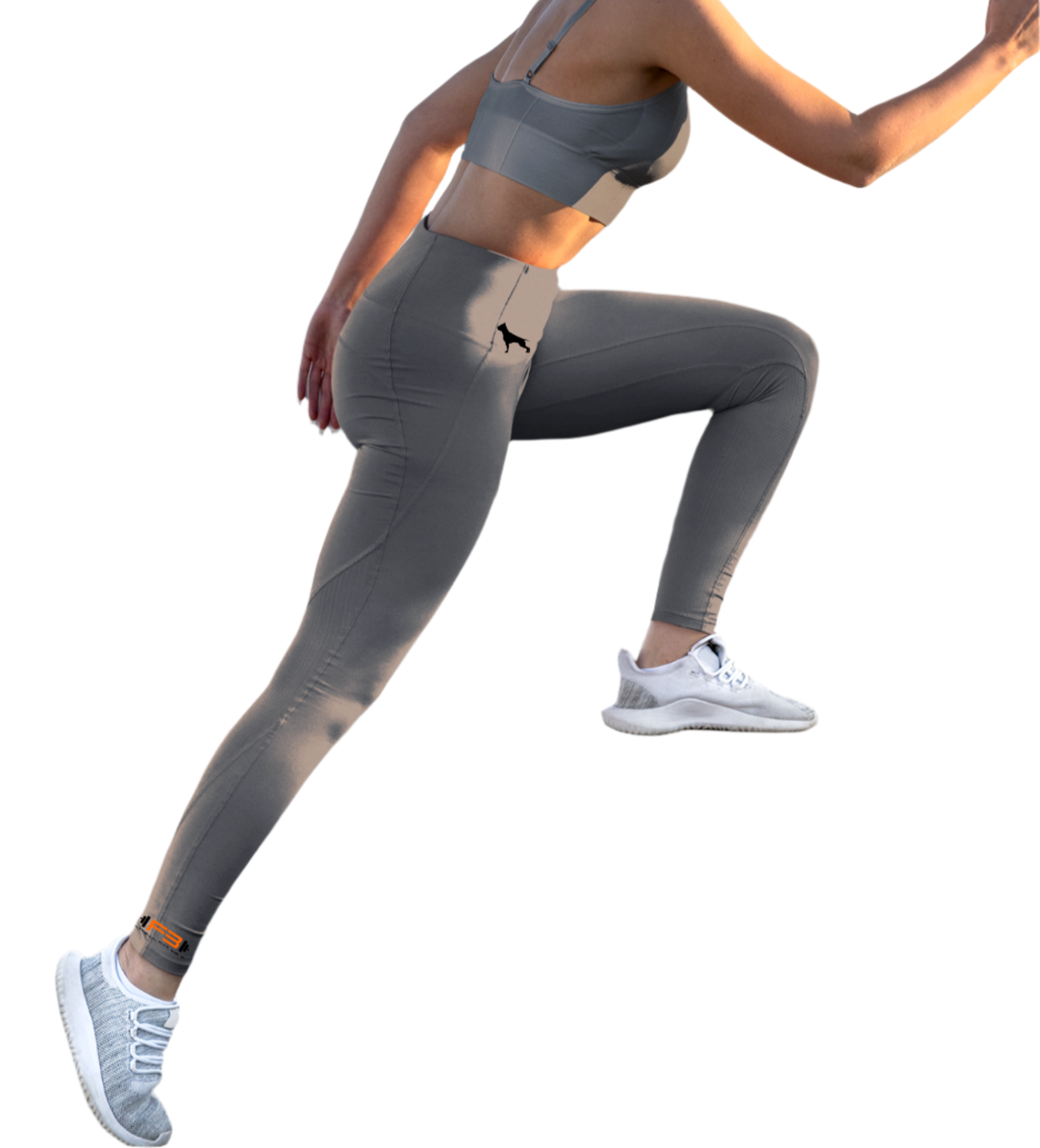 Eine Frau in grauen Fitness-Leggings und einem grauen Fitbull-BH, Frontansicht, macht eine Beinübung